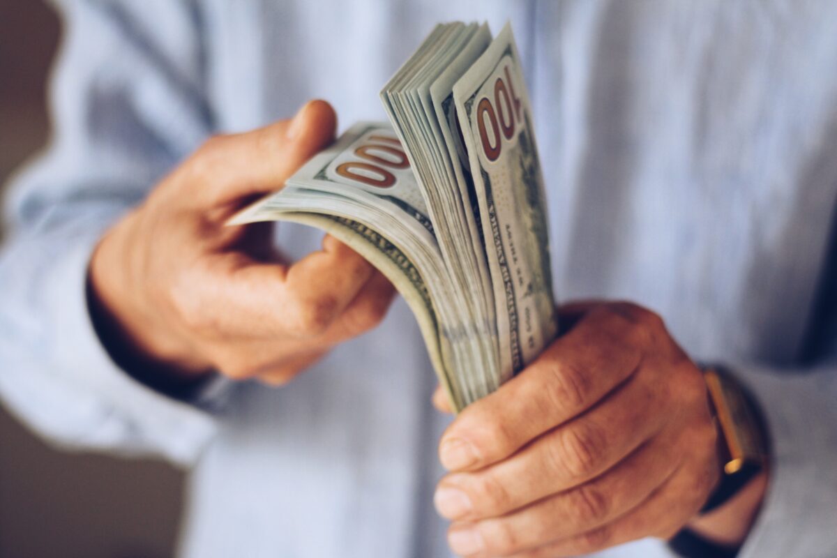 Un hombre cuenta un fajo de dólares para representar a los hombres más ricos del mundo.